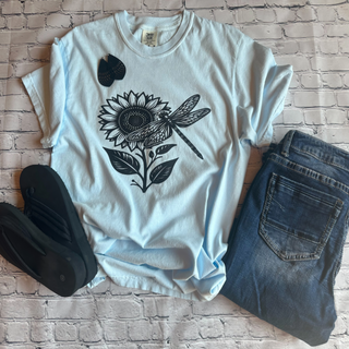 This is the Sunflower Dragonfly Graphic Tee in the color soft baby blue. The brand is Comfort Colors. It is presented as a flat lay.